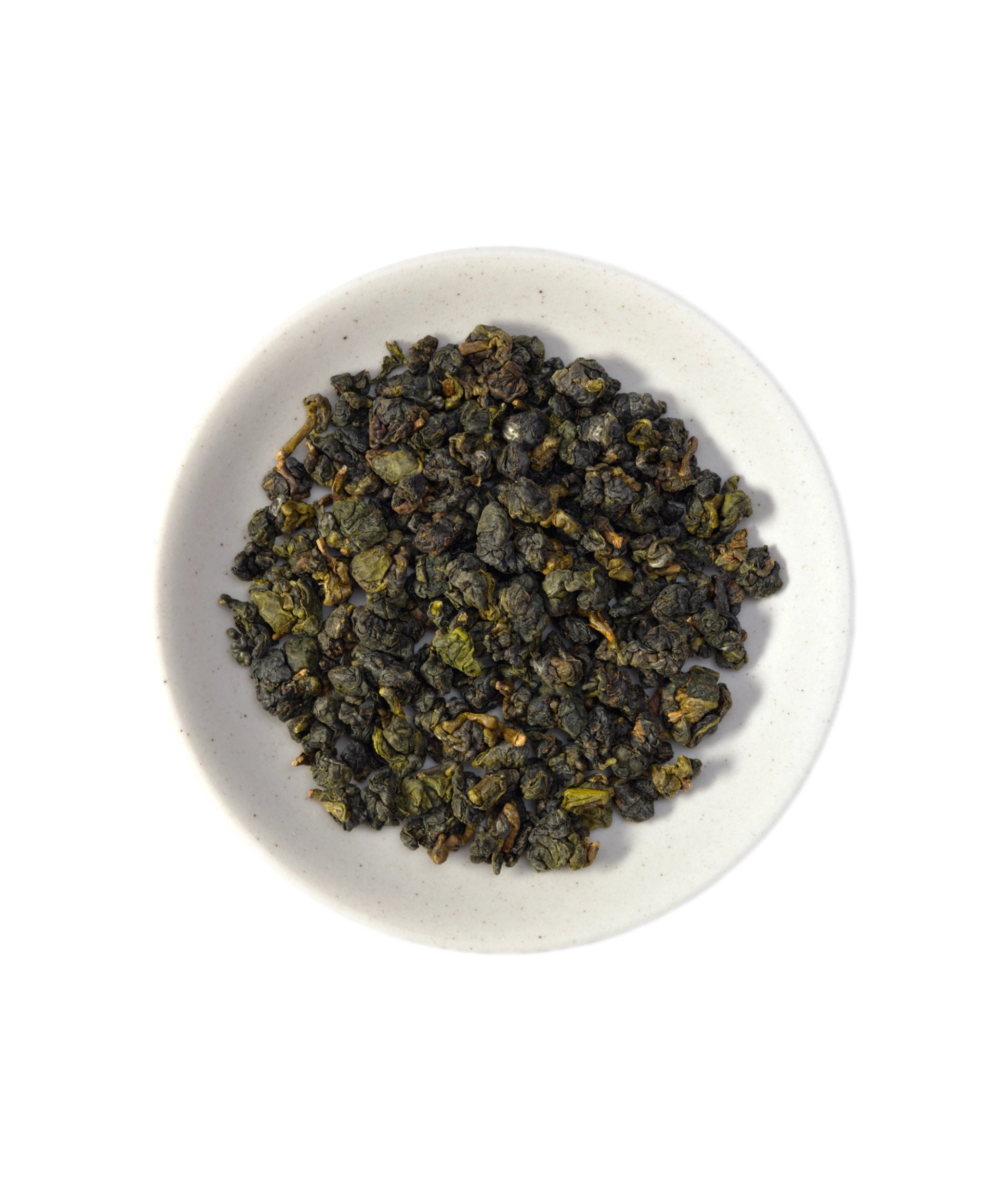 Dry green tea leaves in a white bowl on a white background